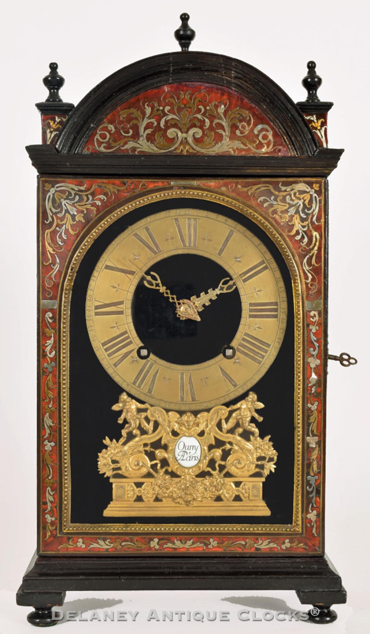 A French bracket or mantel clock with a red boulle facade inlaid with brass scrollwork. The enamel cartouche signed, "JUHEL / A VERSAILLES." The Maker engraves the back plate "Ourry / A Paris." YY-56.