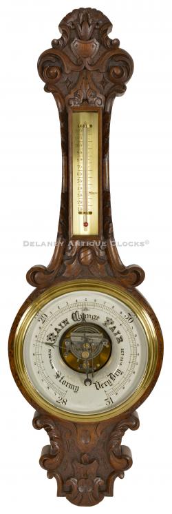 A very unusual carved walnut case aneroid barometer. 222101.