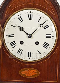 A mahogany case shelf or mantel clock with decorative inlays. 